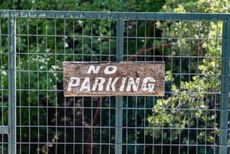 A wooden no parking sign on a gate.