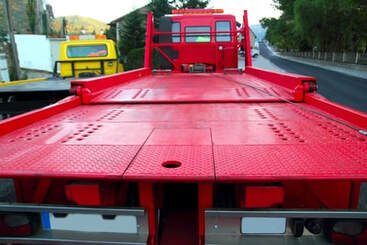 The back of a red flat bed tow truck.